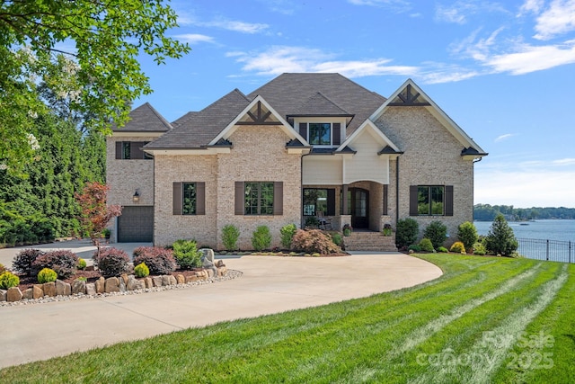 craftsman house featuring a water view, a garage, and a front lawn