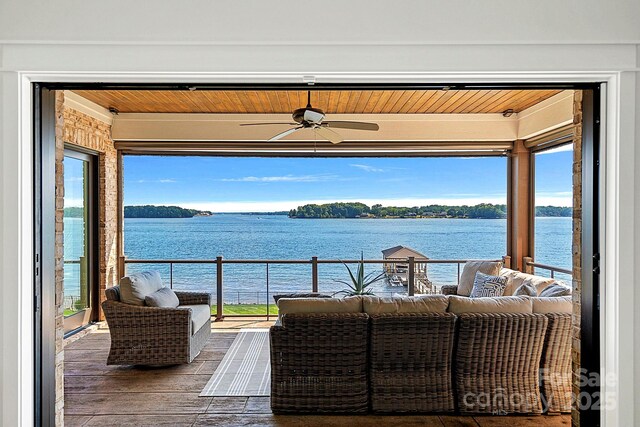 interior space with ceiling fan, a water view, and an outdoor living space