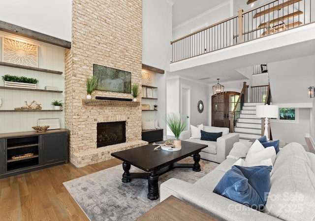 living room featuring light hardwood / wood-style floors, a high ceiling, and a brick fireplace