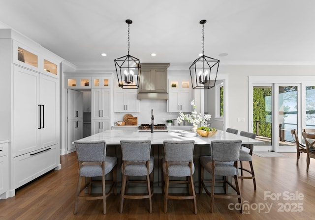 kitchen featuring a kitchen bar, light stone counters, hanging light fixtures, and a large island