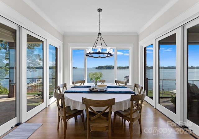 sunroom featuring a chandelier, french doors, a water view, and a wealth of natural light