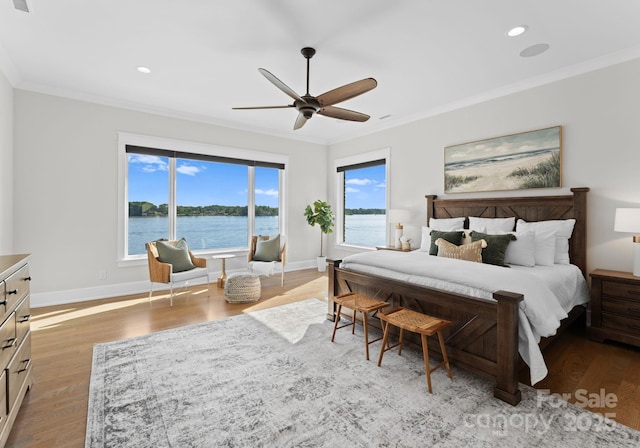 bedroom with ceiling fan, light hardwood / wood-style flooring, a water view, and crown molding