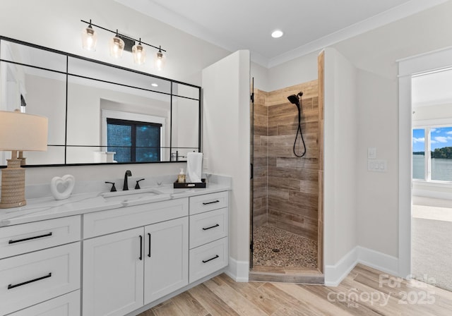 bathroom featuring vanity, a water view, ornamental molding, and tiled shower