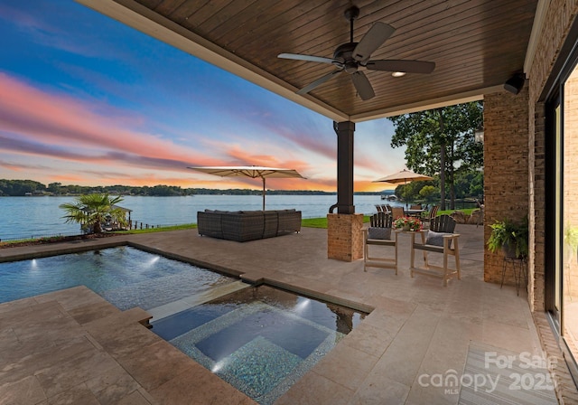 pool at dusk featuring an in ground hot tub, an outdoor hangout area, ceiling fan, a water view, and a patio