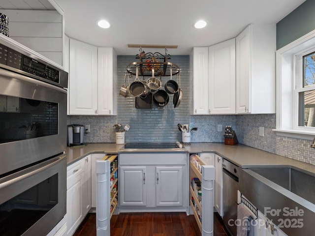 kitchen featuring black electric cooktop, dark wood-type flooring, double oven, and white cabinets