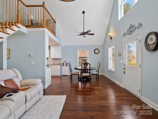 living room featuring ceiling fan, dark hardwood / wood-style floors, and a high ceiling