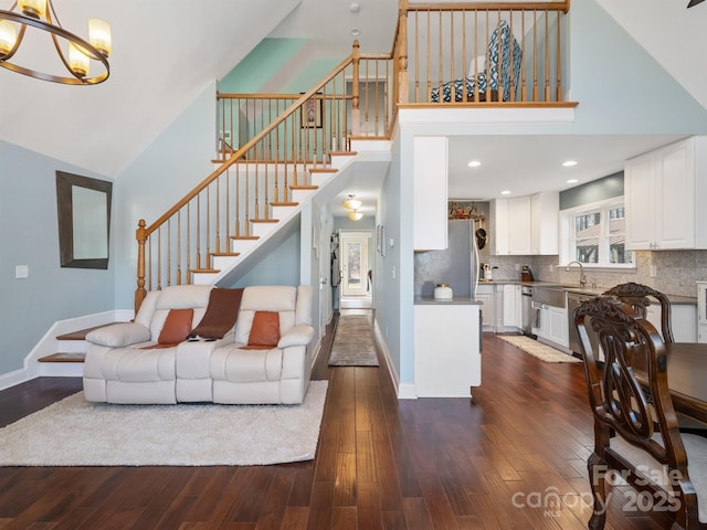 living room with high vaulted ceiling, dark wood-type flooring, sink, and a chandelier