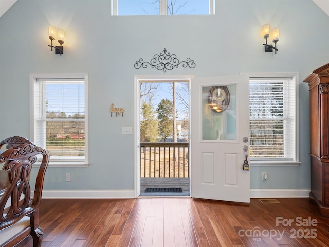 foyer entrance with a towering ceiling, visible vents, baseboards, and dark wood-type flooring