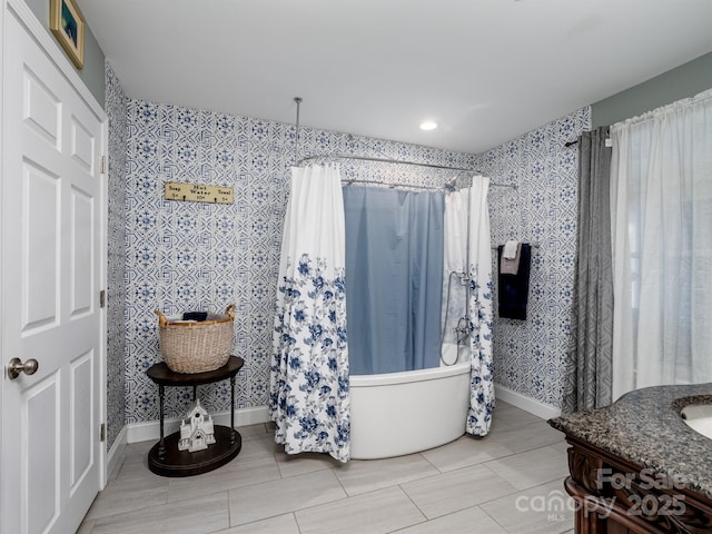 bathroom featuring baseboards, vanity, and wallpapered walls