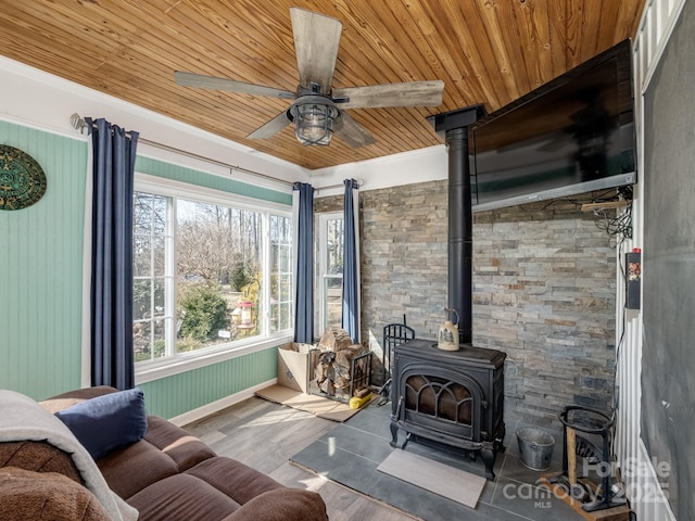 living area with a wood stove, wood ceiling, ceiling fan, and wood finished floors