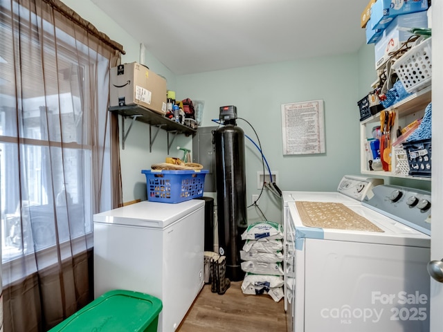 washroom with laundry area, washing machine and dryer, a wealth of natural light, and wood finished floors