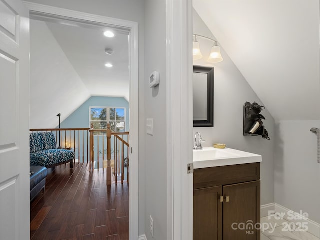 bathroom featuring hardwood / wood-style flooring, vanity, and vaulted ceiling