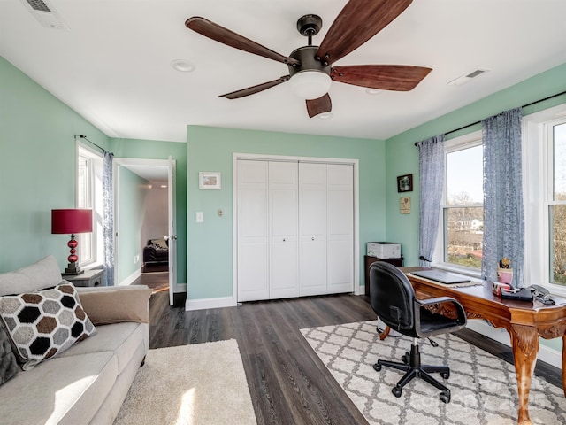 home office with a ceiling fan, visible vents, dark wood finished floors, and baseboards