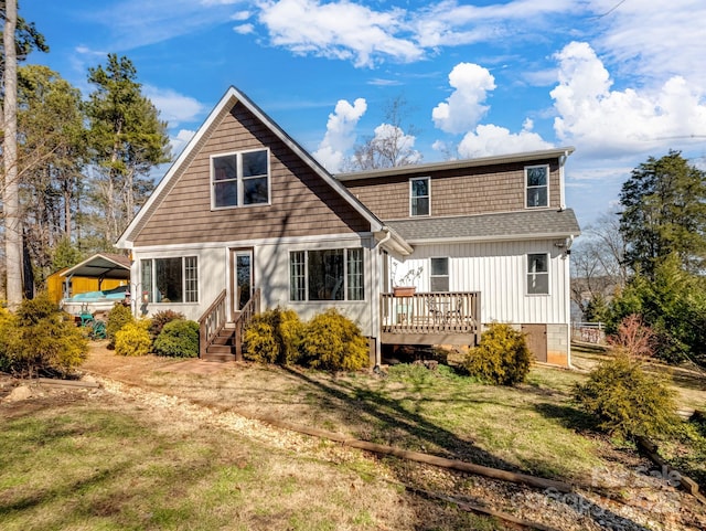 rear view of property with roof with shingles, board and batten siding, a wooden deck, and a lawn