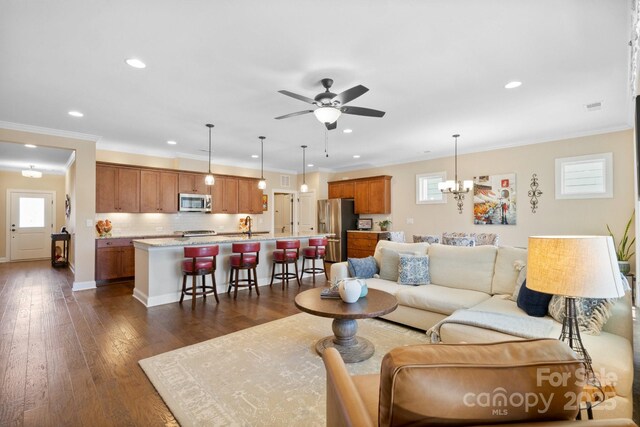 living room featuring ceiling fan with notable chandelier, sink, a wealth of natural light, and dark hardwood / wood-style floors