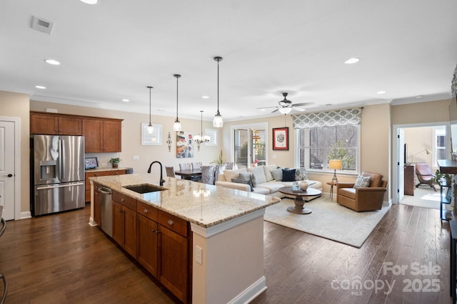 kitchen featuring ceiling fan, a center island with sink, sink, ornamental molding, and stainless steel appliances