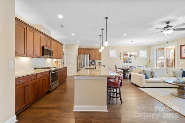 kitchen featuring a kitchen breakfast bar, an island with sink, stainless steel appliances, dark hardwood / wood-style flooring, and light stone counters