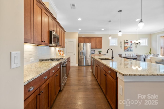 kitchen featuring an island with sink, stainless steel appliances, tasteful backsplash, hanging light fixtures, and sink