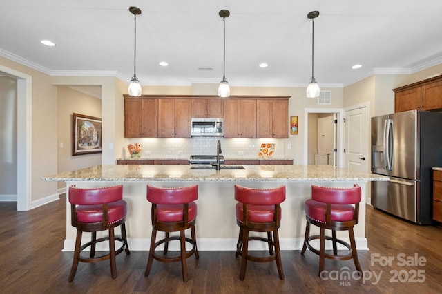 kitchen with decorative backsplash, decorative light fixtures, appliances with stainless steel finishes, and a center island with sink