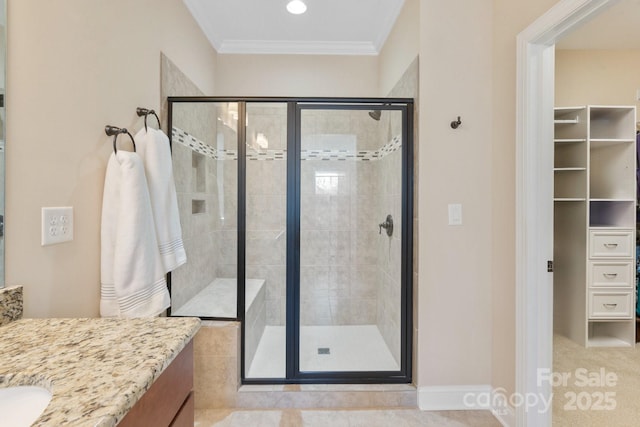 bathroom featuring vanity, a shower with door, and ornamental molding