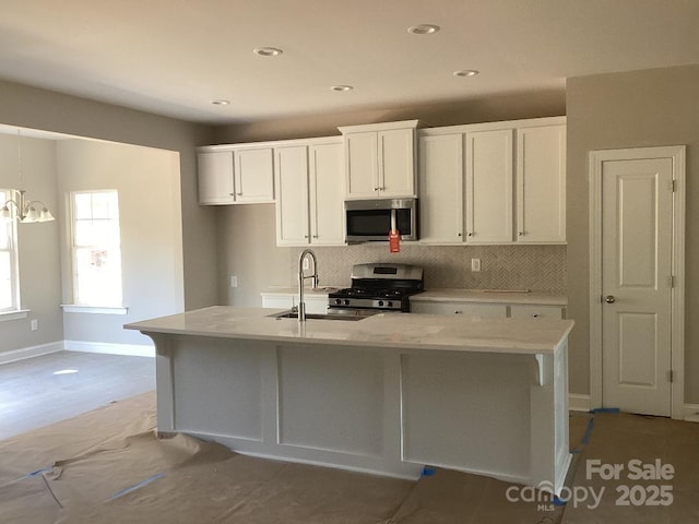 kitchen featuring white cabinetry, sink, appliances with stainless steel finishes, and an island with sink