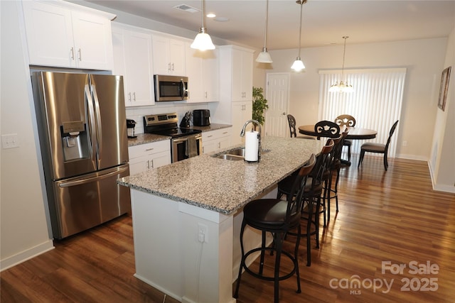 kitchen featuring white cabinetry, sink, an island with sink, pendant lighting, and appliances with stainless steel finishes