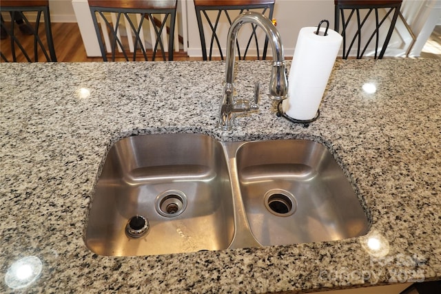 interior details featuring sink, backsplash, and light stone countertops