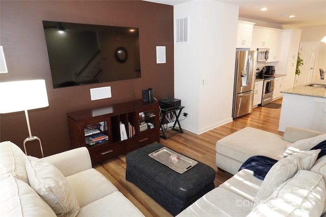 living room featuring sink and light hardwood / wood-style floors