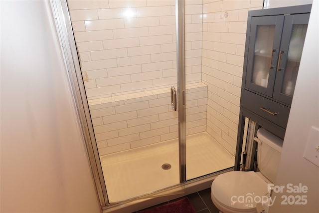 bathroom featuring toilet and a shower with door