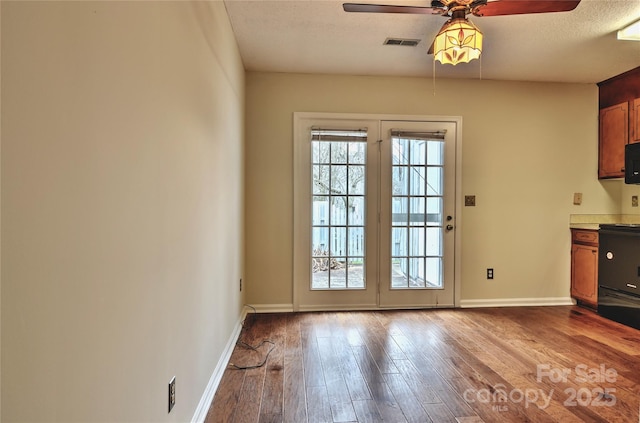 doorway to outside featuring ceiling fan, light hardwood / wood-style floors, and a textured ceiling