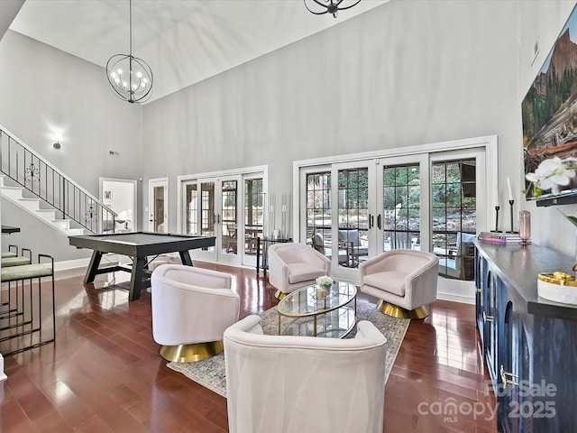 living room featuring a high ceiling, dark wood-type flooring, french doors, an inviting chandelier, and billiards