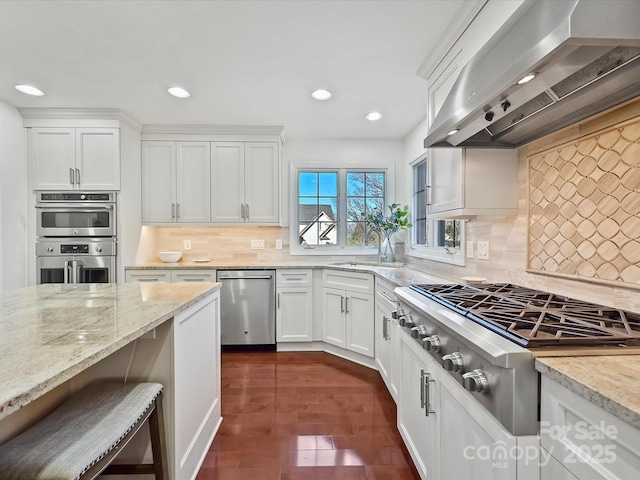 kitchen featuring backsplash, white cabinetry, appliances with stainless steel finishes, and wall chimney exhaust hood