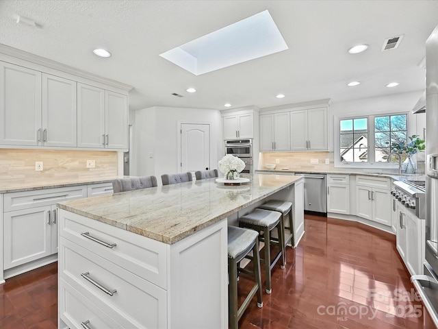 kitchen featuring a kitchen breakfast bar, a skylight, and white cabinetry