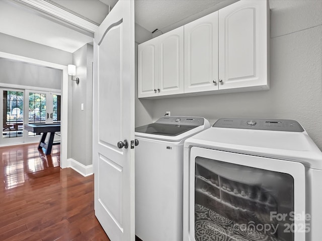 laundry area featuring cabinets, dark hardwood / wood-style flooring, and washing machine and clothes dryer