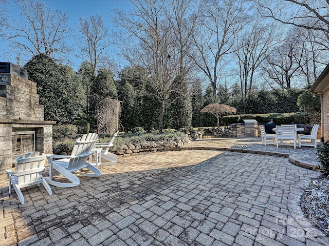 view of patio / terrace with grilling area, an outdoor stone fireplace, and exterior kitchen