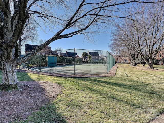 view of sport court featuring tennis court and a lawn