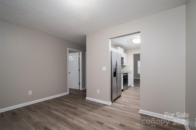 hallway with a textured ceiling and light hardwood / wood-style floors