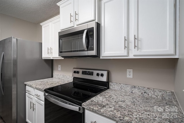 kitchen featuring light stone countertops, white cabinetry, stainless steel appliances, and a textured ceiling