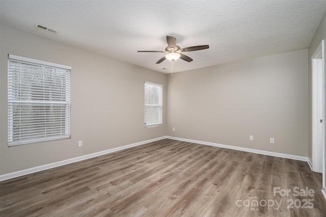 empty room featuring ceiling fan, wood-type flooring, and a textured ceiling