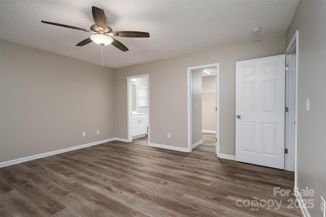 unfurnished bedroom featuring a spacious closet, a textured ceiling, ensuite bath, a closet, and ceiling fan