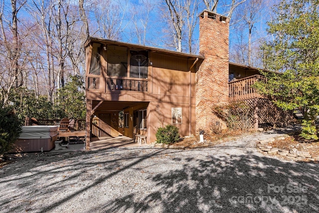 rear view of property with a hot tub, a wooden deck, and a sunroom