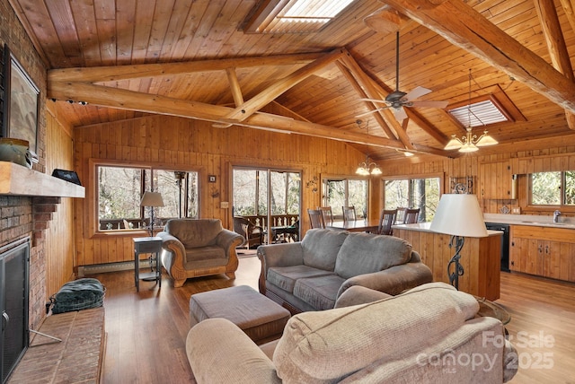 living room featuring beam ceiling, a skylight, wooden ceiling, and a brick fireplace