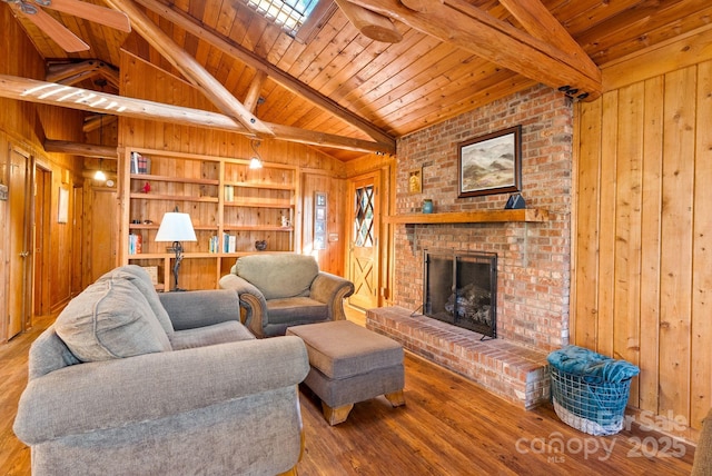 living room with a fireplace, vaulted ceiling with skylight, wooden walls, and wood ceiling