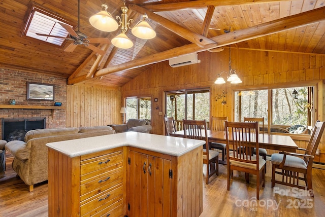 kitchen featuring light wood-type flooring, a skylight, wood ceiling, a wall mounted AC, and beamed ceiling