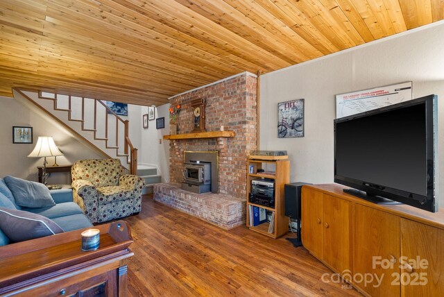 living room with hardwood / wood-style flooring, wood ceiling, and a wood stove