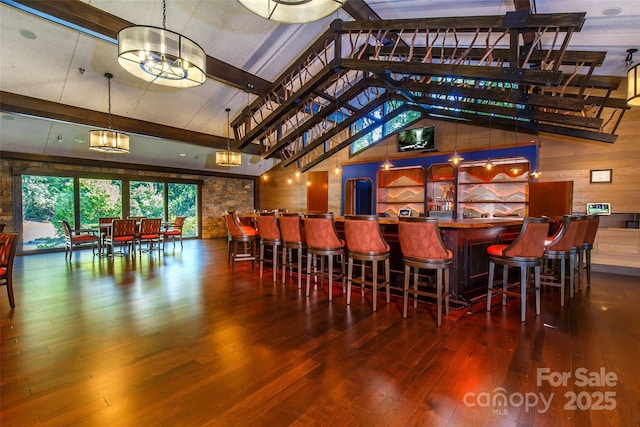 bar with high vaulted ceiling, an inviting chandelier, wooden walls, hardwood / wood-style flooring, and beam ceiling