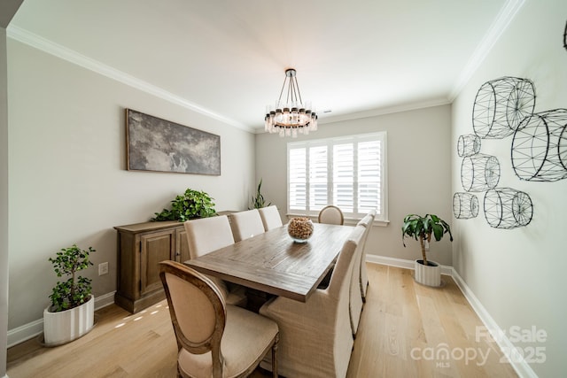 dining room featuring a notable chandelier, ornamental molding, and light hardwood / wood-style flooring