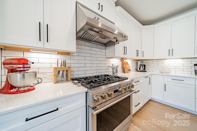 kitchen with high end stainless steel range, white cabinets, and extractor fan