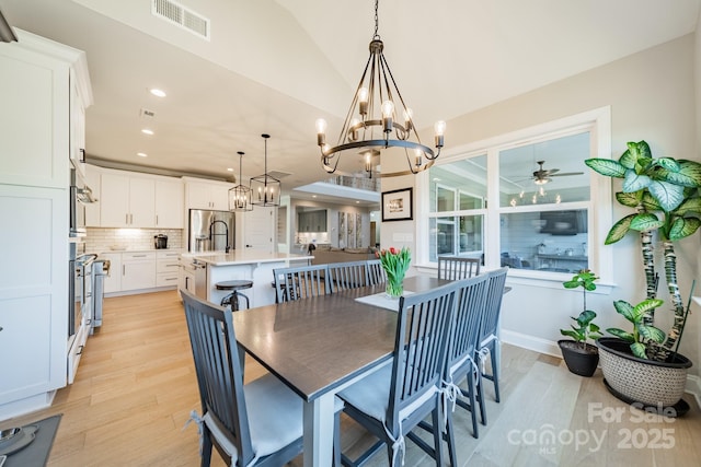 dining room with ceiling fan, lofted ceiling, and light hardwood / wood-style flooring