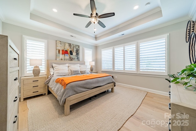 bedroom with a raised ceiling, ceiling fan, ornamental molding, and light hardwood / wood-style floors